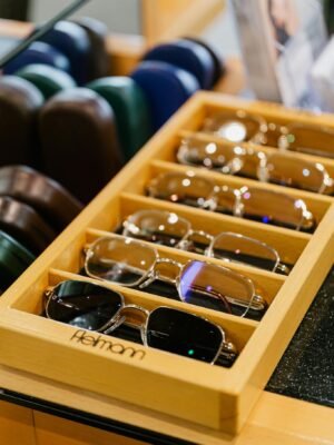 A collection of eyeglasses neatly arranged in a wooden tray at an eyewear store.