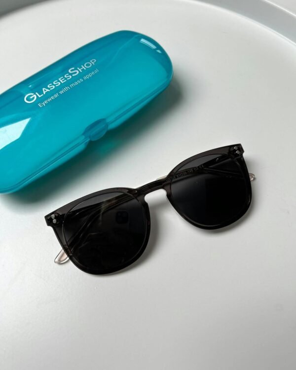 Elegant black sunglasses with a blue case on white surface, perfect for modern summer fashion.