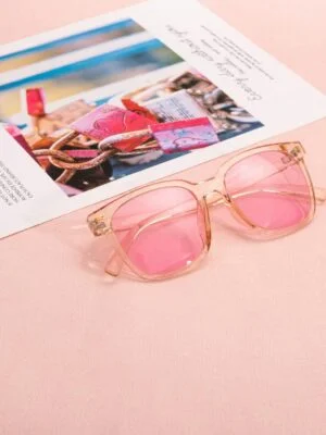 Pink sunglasses on a magazine page with a soft pastel background, capturing a chic and modern vibe.