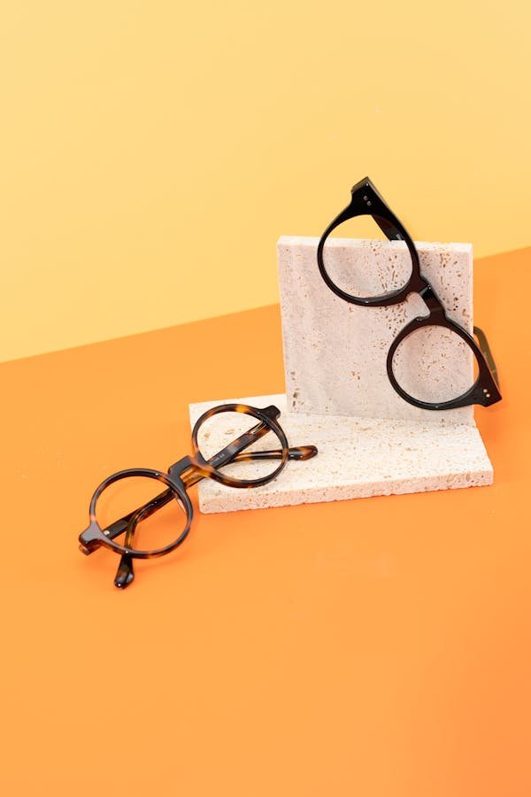 Stylish round eyeglasses on a minimalist concrete and colorful backdrop.